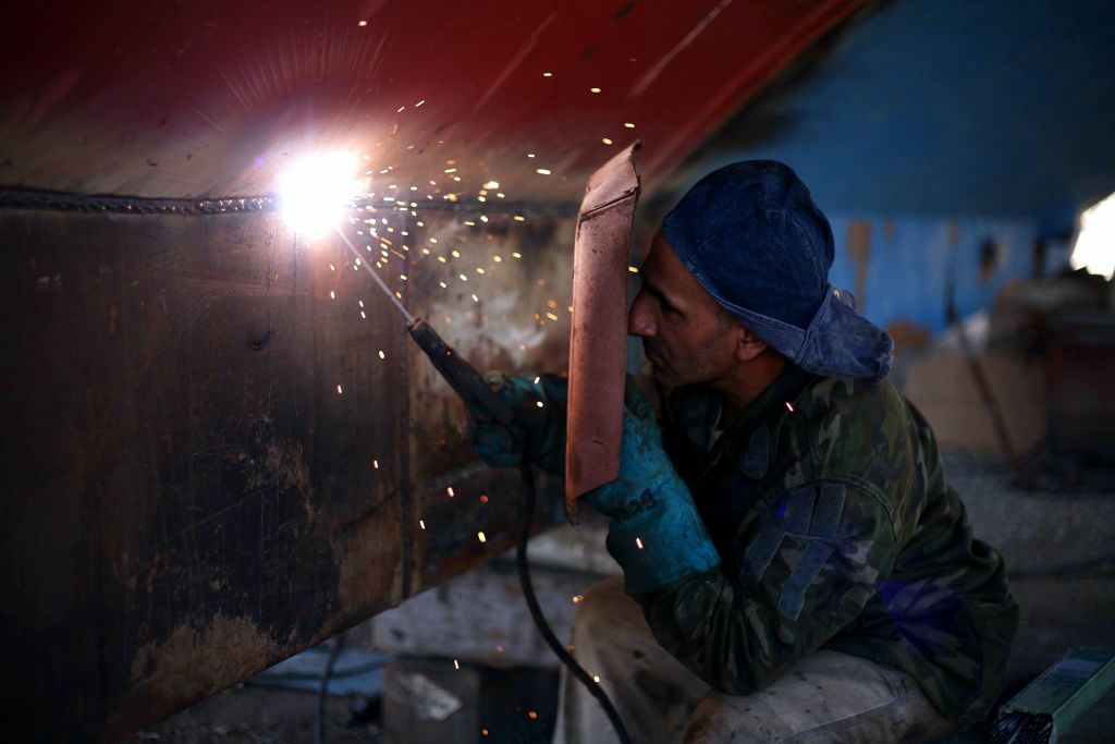 Soldador trabajando una pieza de acero entre chispas